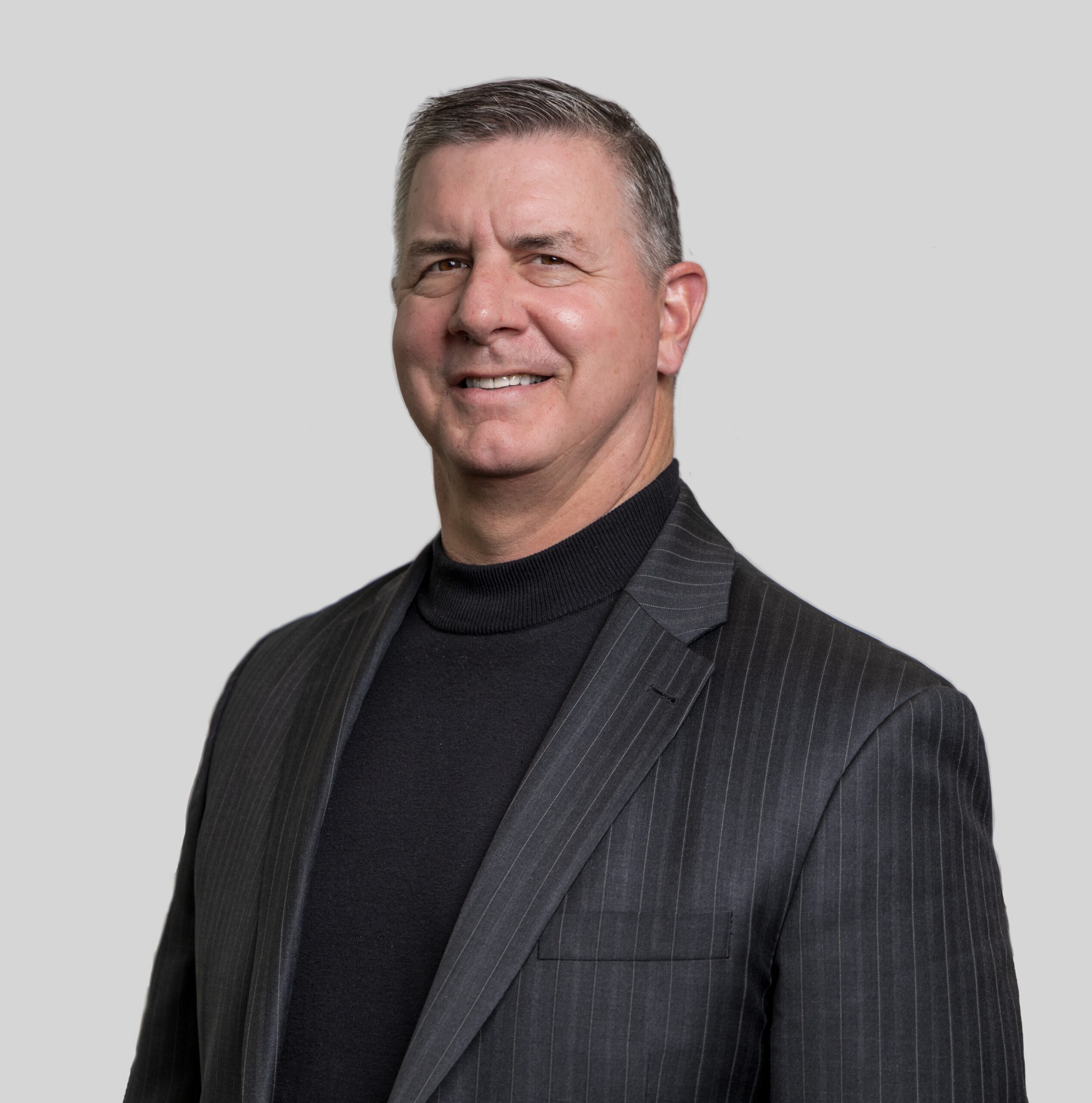 Smiling man in a dark pinstripe suit.